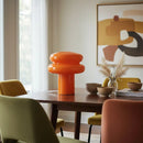 Dining room with a wooden table, colorful chairs, and abstract art on the wall.