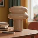 Beige ceramic lamp on a wooden table with books and a pen in a home setting