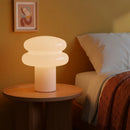 Decorative lamp on a wooden side table in a cozy bedroom setting.
