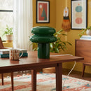 Green lamp on a wooden table with a cozy room setting
