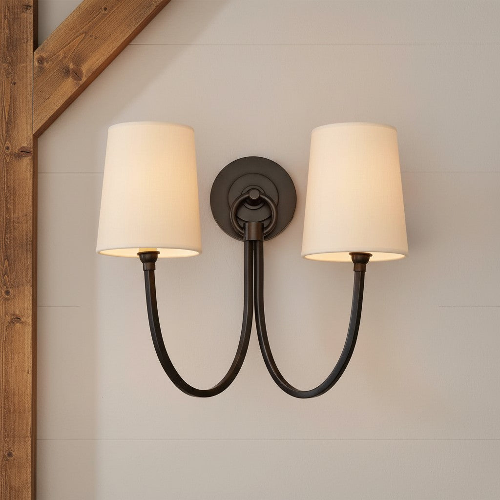 Double wall sconce with two light bulbs on a neutral wall.