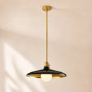 A modern pendant light fixture with a black dome-shaped shade, gold-toned metal frame and canopy, and a glowing warm white globe bulb, suspended from a ceiling against a warm beige wall.