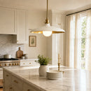 Modern kitchen with marble island, pendant light, and large window.