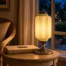 Decorative table lamp on a wooden table with a book, in a cozy room setting.