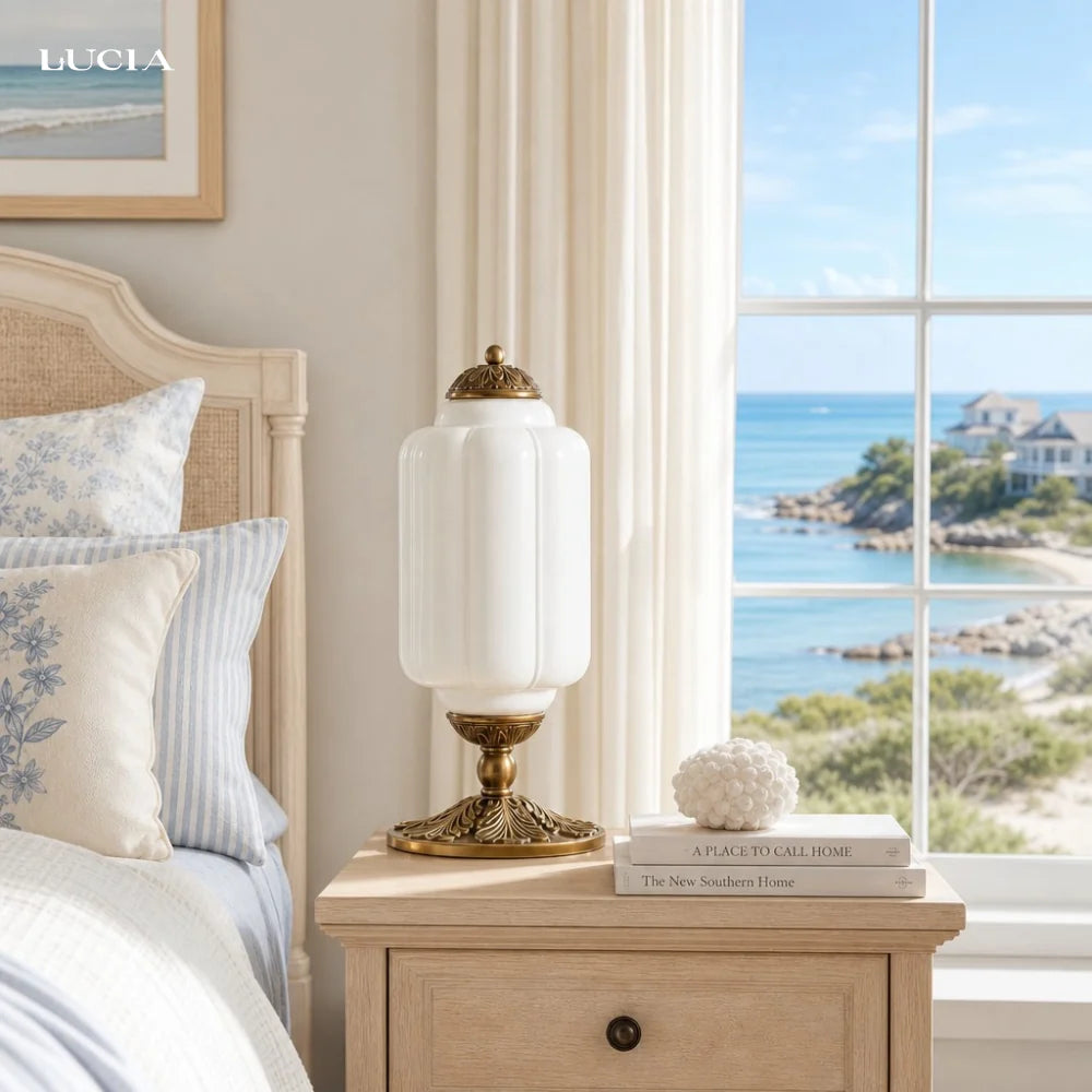 Bedroom with a bedside table, lamp, and view of the ocean through a window.