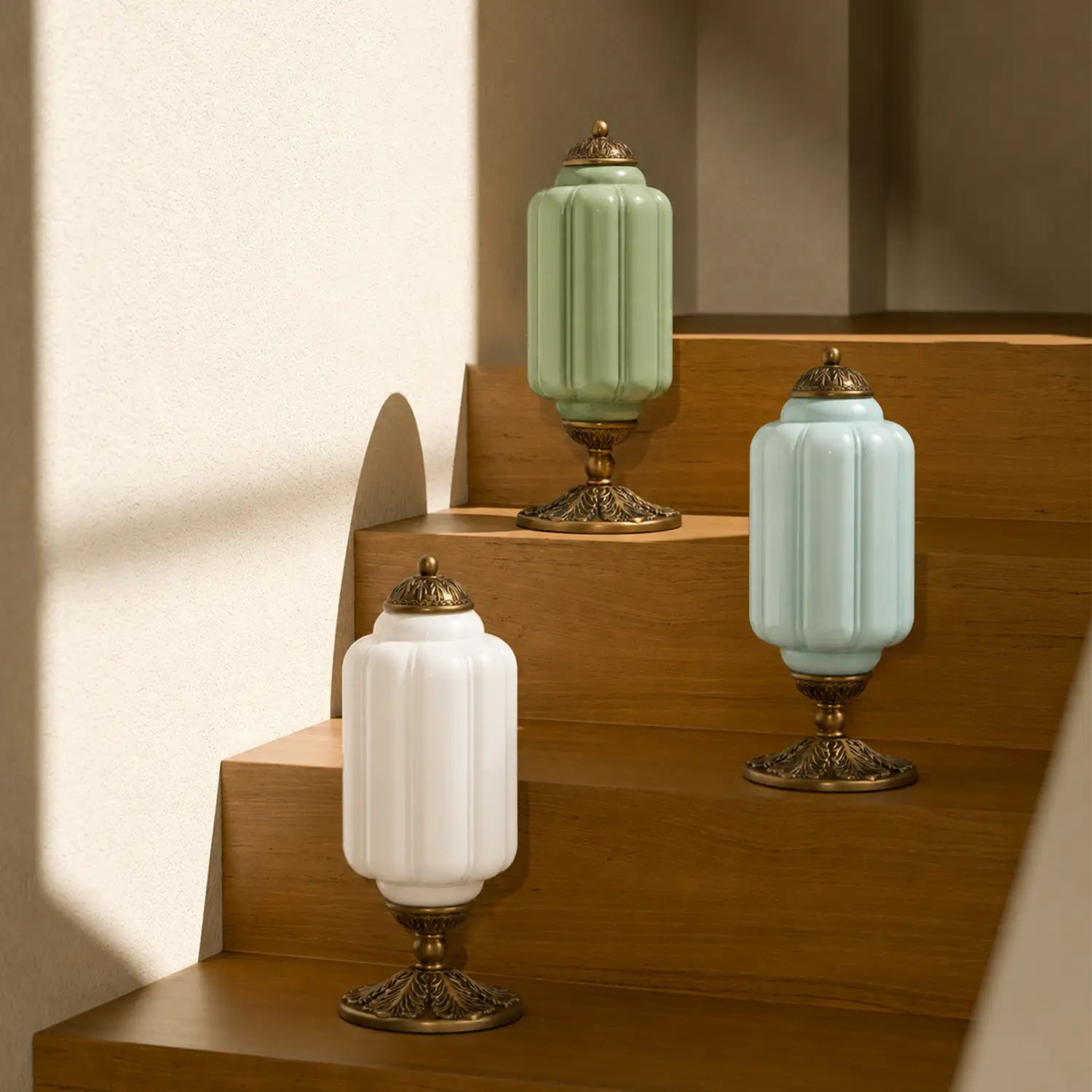 Three decorative lamps with green, white, and gold bases on a wooden shelf.