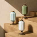 Three decorative lamps with green, white, and gold bases on a wooden surface.