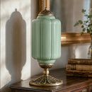 Decorative green lamp with gold base on a wooden surface
