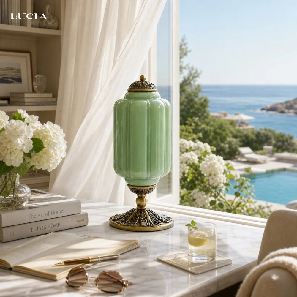 Green lamp on a table with a scenic view of a pool and ocean.