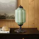 Decorative green lamp with black base on a wooden surface