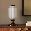 Decorative table lamp with white glass shade and brass base on a wooden surface.