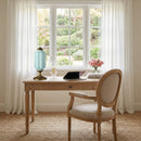 Wooden desk with chair in a room with large windows and garden view