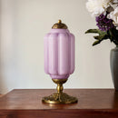 Decorative table lamp with a purple glass shade and gold base on a wooden surface.
