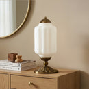 Decorative table lamp with white glass shade and gold base on a wooden surface.