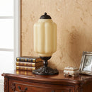 Decorative table lamp on a wooden surface with books and a photo frame in the background.