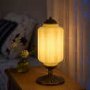 Decorative table lamp with a warm glow on a wooden surface, with a blurred background.