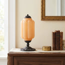 Vintage-style table lamp with an orange glass shade on a wooden surface.