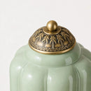 Green ceramic jar with a detailed bronze lid on a white background