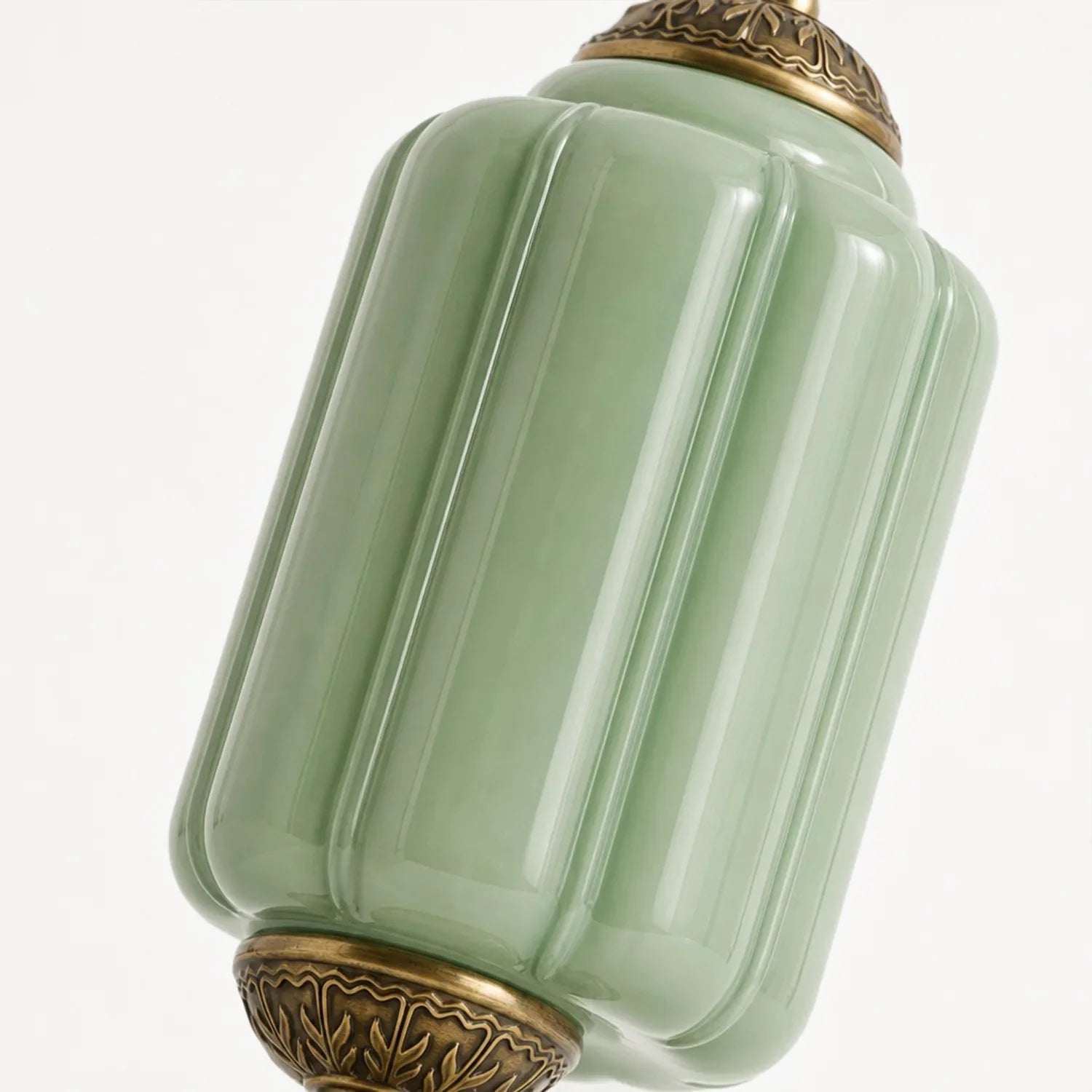 Green ceramic jar with gold decorative elements on a white background