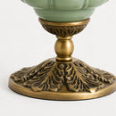 Decorative lamp base with intricate brass design on a white background