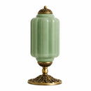 Decorative lamp with green glass and gold metal base on a white background