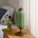 Decorative green lamp with gold base on a wooden surface
