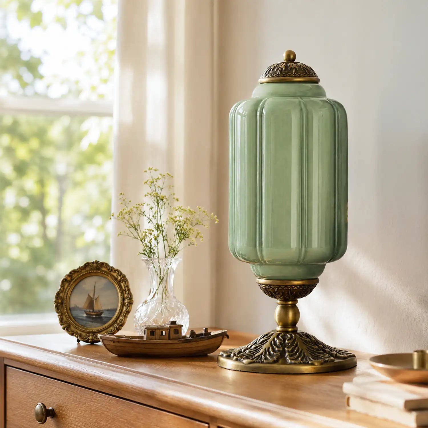 Decorative green lamp with gold base on a wooden surface near a window.