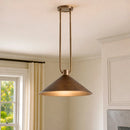 Bronze pendant light hanging in a room with a window and white walls.