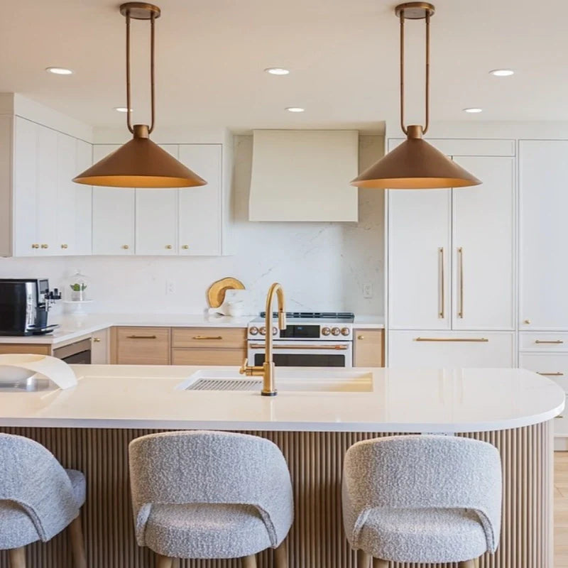 Modern kitchen with white island, gold fixtures, and pendant lights.