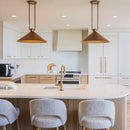 Modern kitchen with white island, gold fixtures, and pendant lights.
