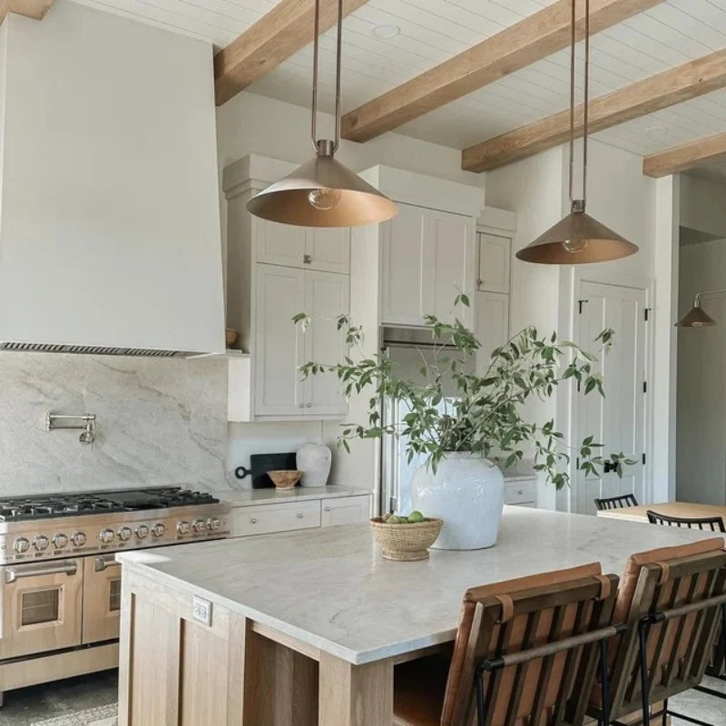 Modern kitchen with marble island, wooden beams, and pendant lights.