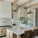 Modern kitchen with marble island, wooden beams, and pendant lights.