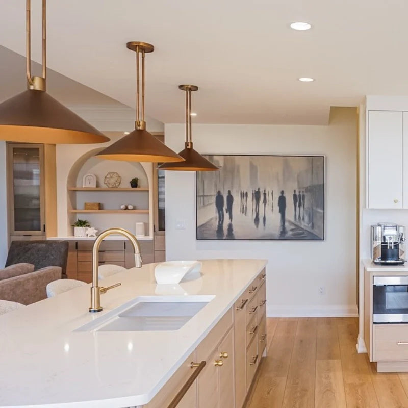 Modern kitchen with white countertops, gold pendant lights, and a wall art piece.
