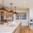 Modern kitchen with white countertops, gold pendant lights, and a wall art piece.