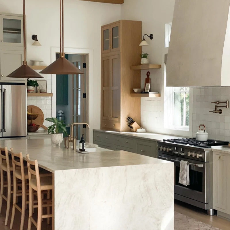 Modern kitchen with marble island, stainless steel appliances, and wooden chairs.