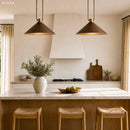 Modern kitchen with pendant lights, a vase with plants, and wooden stools.
