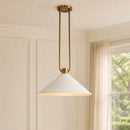 Pendant light fixture with white shade and gold accents in a room with a window.