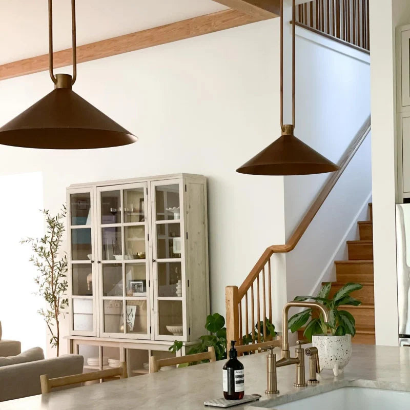 Modern kitchen with pendant lights, a staircase, and a dining area.