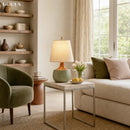 Living room with beige sofa, green armchair, and a lamp on a side table.