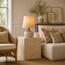 Living room with beige sofa, wicker chair, and decorative lamp.