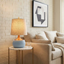 Living room with beige sofa, lamp on a side table, and abstract art on the wall.
