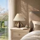 Napoleon Chateau lamp on a nightstand next to a bed with pillows