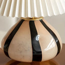 Decorative lamp with black and gold stripes against a neutral background