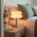 Lamp on a bedside table next to a bed with pillows