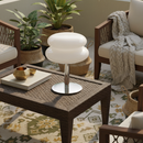 Decorative table lamp on a wicker table with plants and furniture in the background