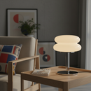 Modern table lamp on a wooden side table with a sofa and artwork in the background