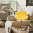 Yellow stool on a wooden table in a living room setting with beige furniture and plants.