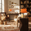 Living room with orange stools, wooden chairs, and a bookshelf.