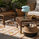 Outdoor patio setting with wicker furniture, plants, and a rug.