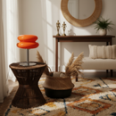 Living room with wicker side table, orange stool, and decorative items.